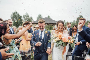 a confetti shot of a couple and their family at an outdoor wedding ceremony